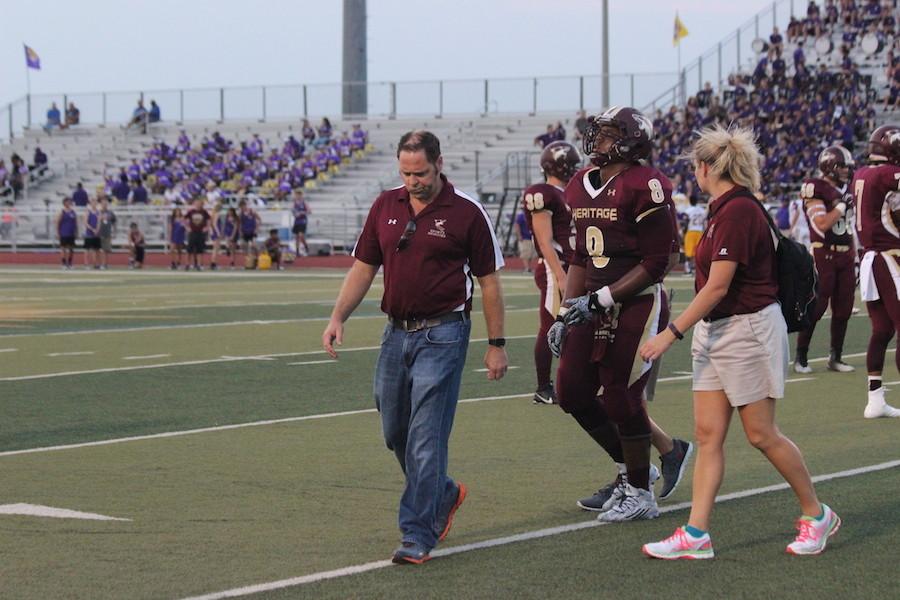Coach Sharpe walks an injured player off the field at the Richardson game.
