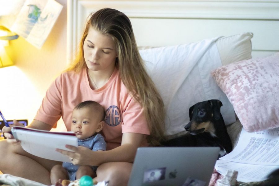 Ainslee Smith, a Heritage High School graduate of the class of 2019, works on her college course while trying to entertain her son, Everett. Anislee gave birth to him back in April 2019 and has been juggling work and being a new mother since.  
